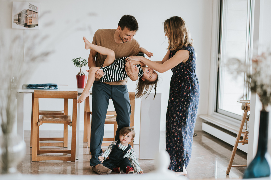 famille naturelle prise en photo dans leur salon par un photographe qui se déplace à domicile pour réaliser des portraits de famille dans un style naturel